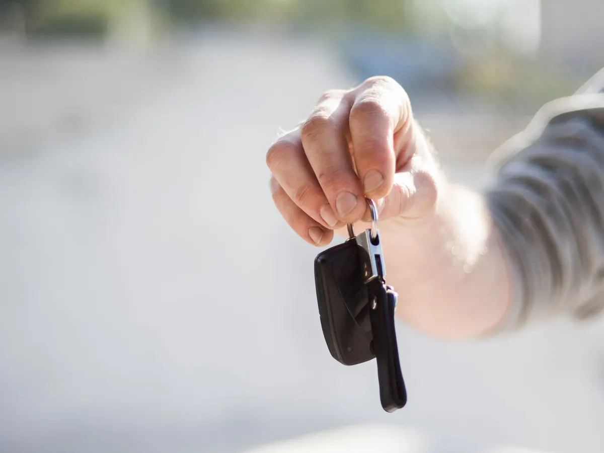 Eine Hand übergibt einen Autoschlüssel